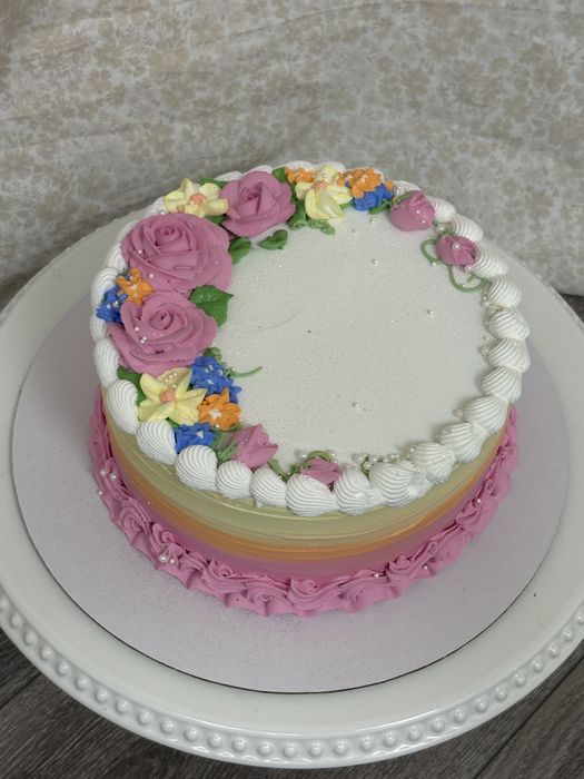 Cake with a wreath of pink buttercream roses and spring flowers
