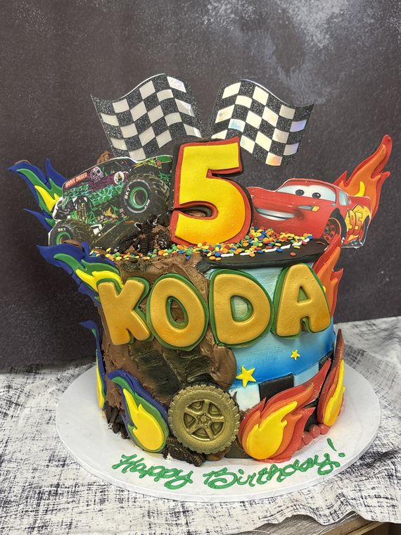 Monster truck and race car birthday cake with checkered flags and flames for Koda turning 5