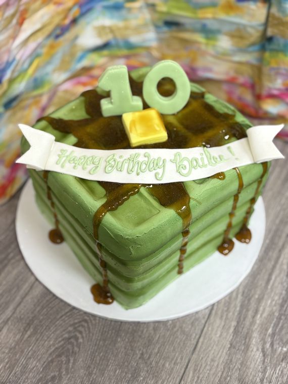 Birthday cake sculpted as a stack of waffles with butter and dripping syrup
