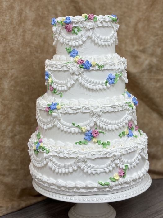 Four-tier vintage buttercream wedding cake with piped garlands and pastel flowers